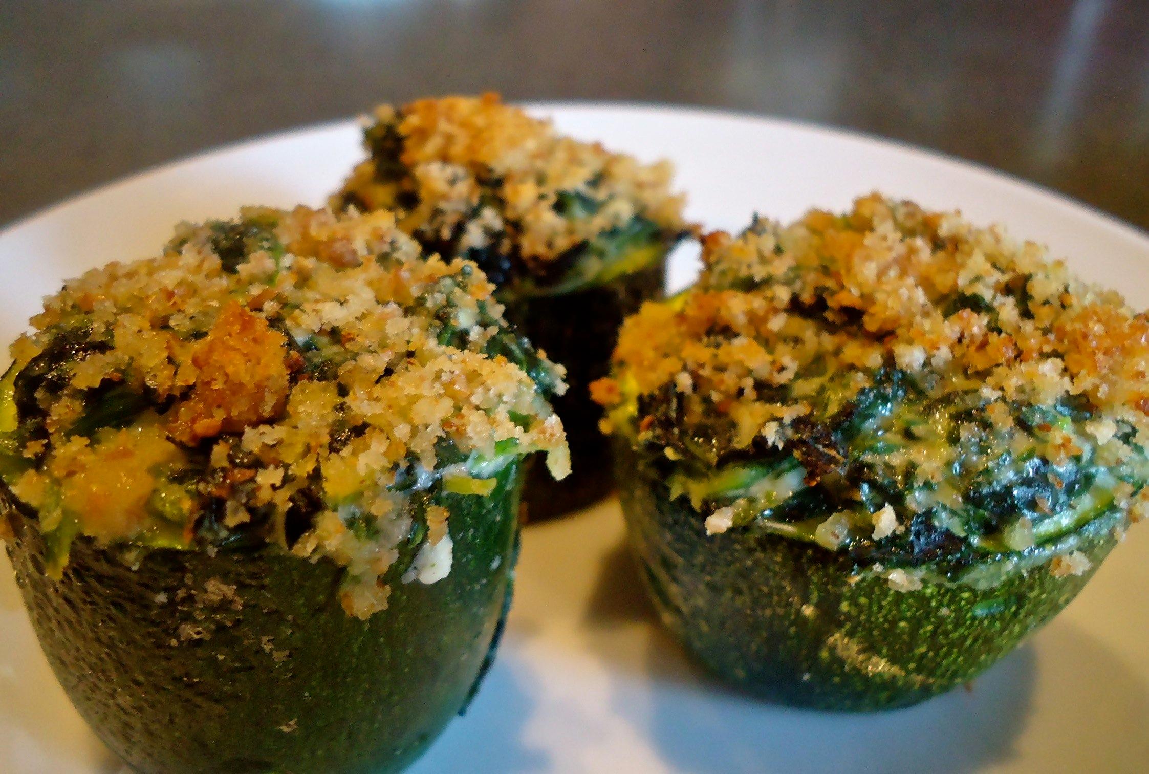 Close-up of filled zucchini cups, sprinkled with parmesan cheese before baking