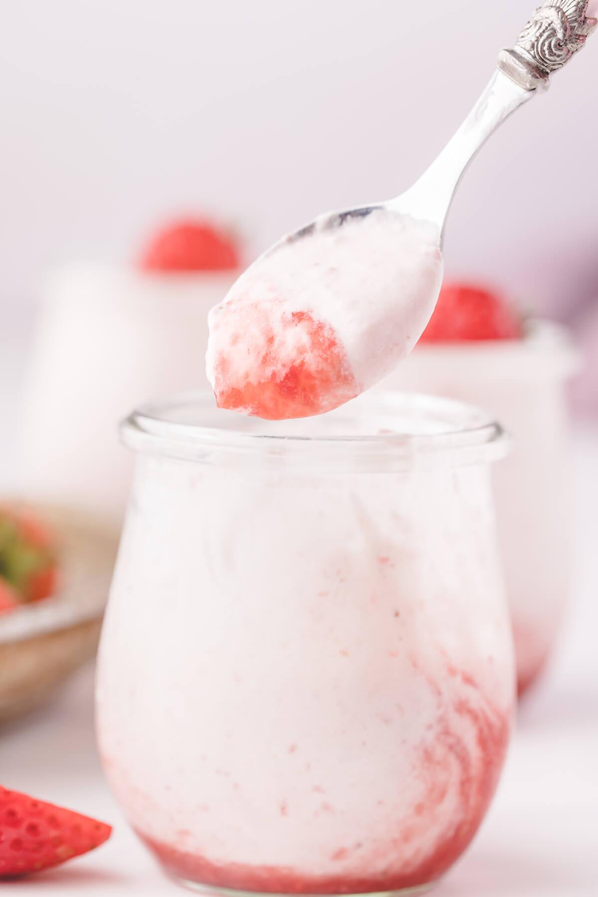 close-up of a spoonful of strawberry mousse being lifted from a glass