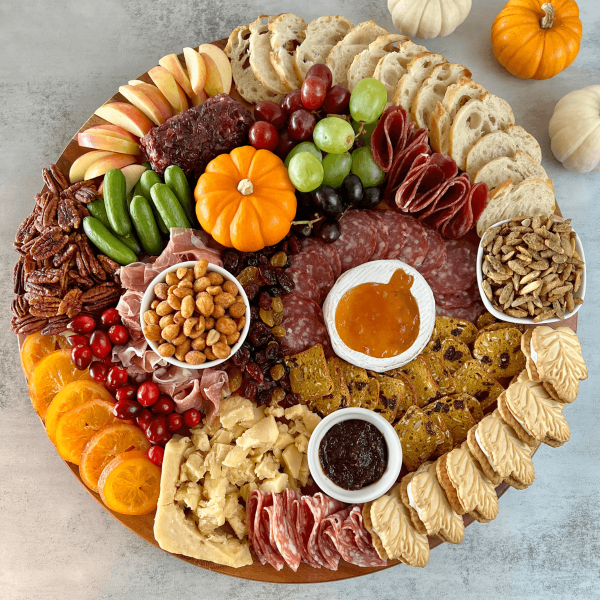 Cranberry and walnut charcuterie board with a variety of cheeses, fruits, and crackers