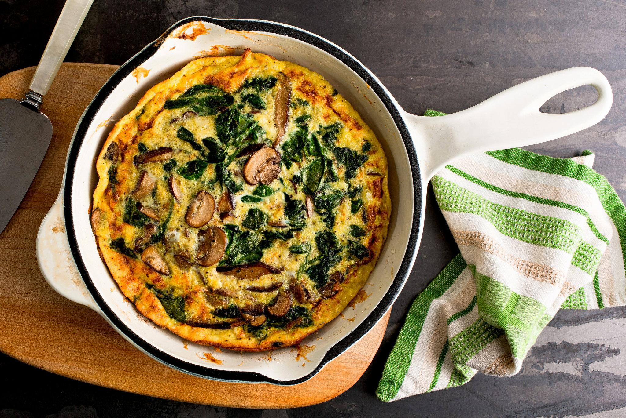 overhead shot of a freshly baked mushroom and spinach frittata in a skillet