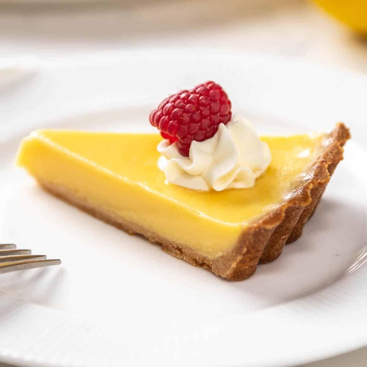 Close-up shot of a slice of keto lemon tart, showing the texture of the crust and the creamy filling.