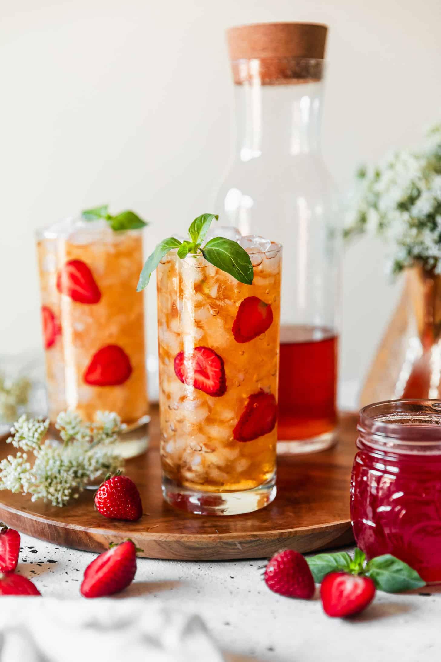 pitcher of strawberry iced tea with sliced strawberries and mint garnish
