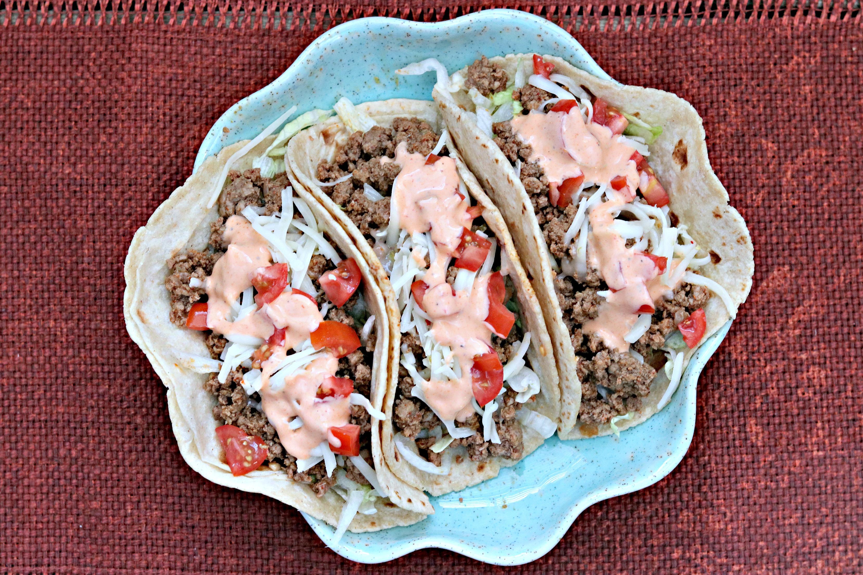 Overhead shot of fully assembled Sriracha Lime Ground Beef Tacos with various toppings