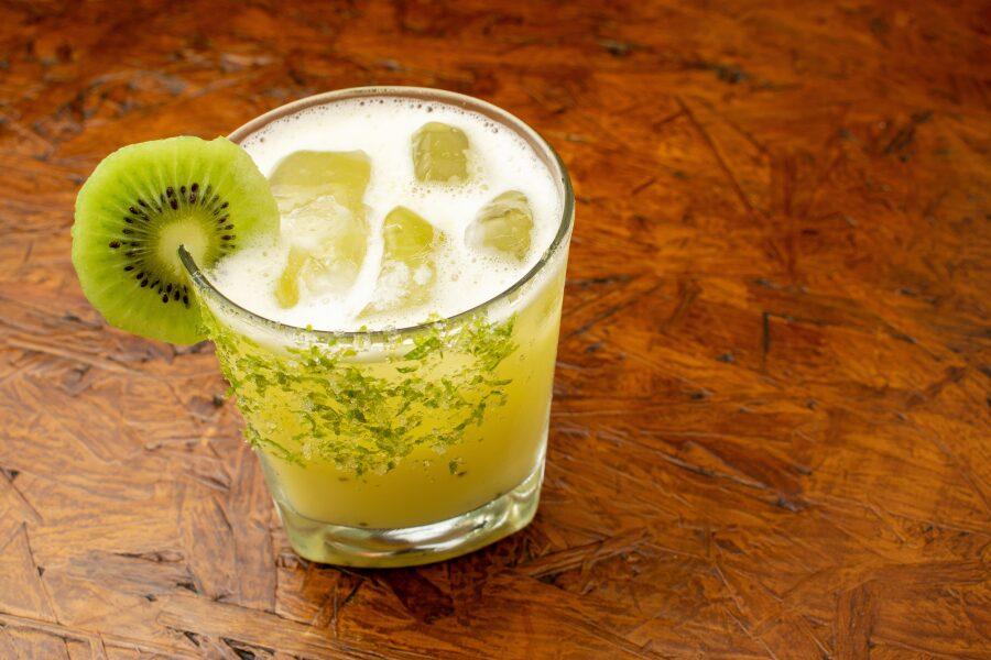 Close-up of a glass of kiwi margarita with ice cubes and a sugar rim