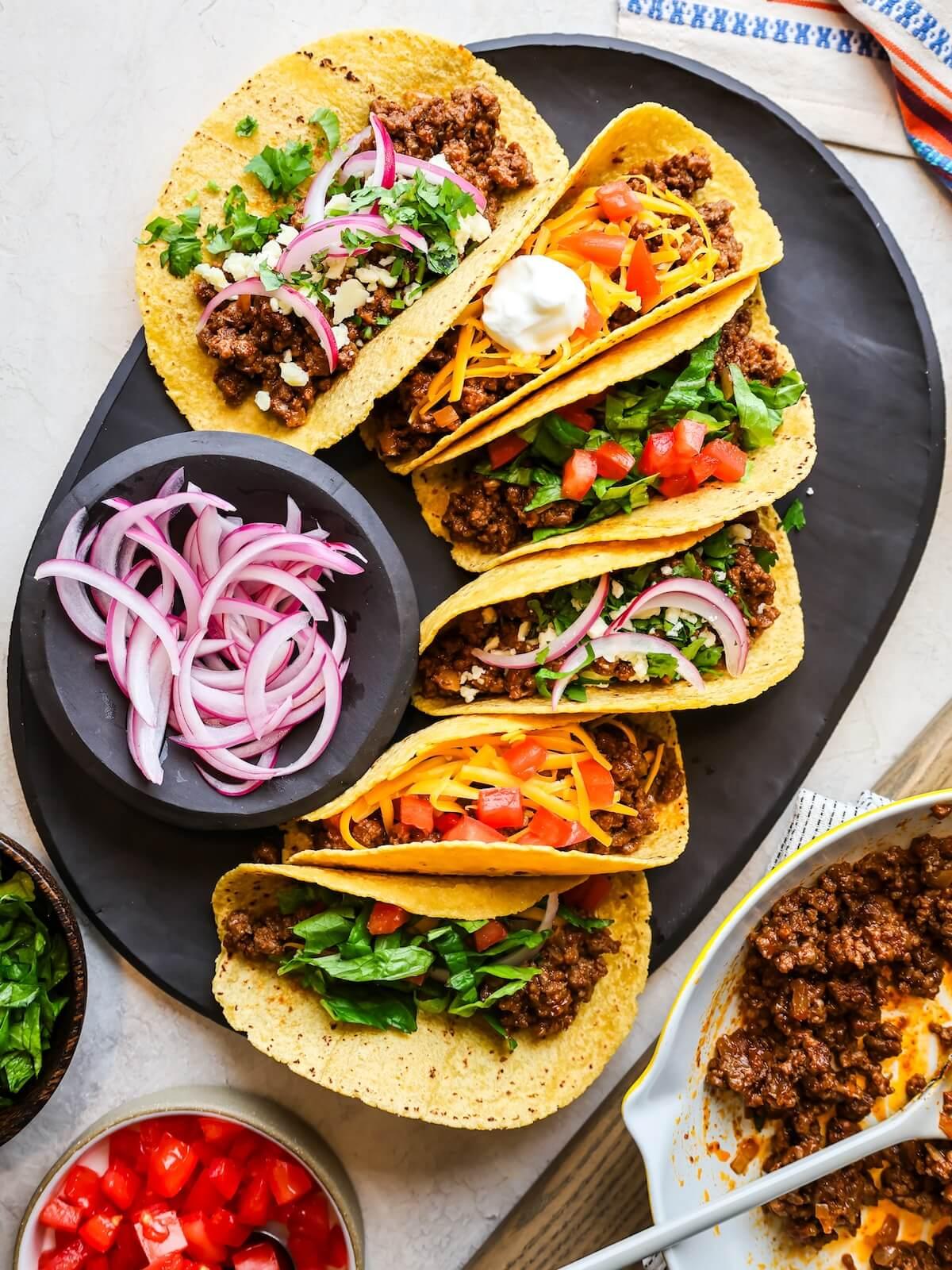 overhead shot of assembled star anise ground beef tacos with various toppings