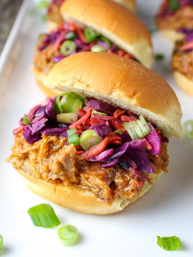 a platter of lemongrass bbq pork sliders with mint leaves and side of coleslaw