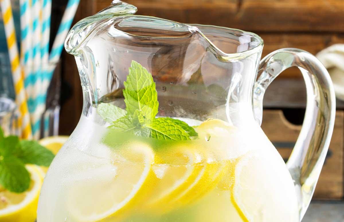 a refreshing pitcher of homemade lemonade with lemon slices and mint garnish