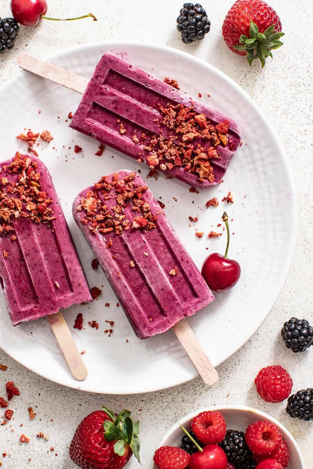 brightly lit sugar plum protein popsicles with fresh berries