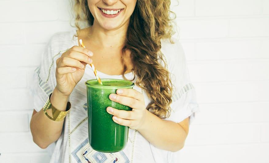 a person happily enjoying a Parsley Peach Green Smoothie, with a bright and sunny background
