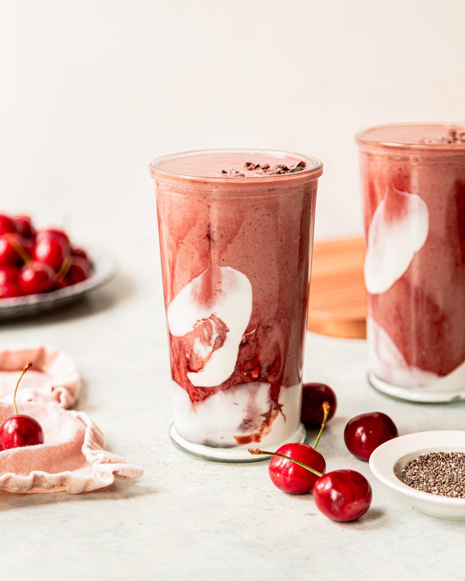 chocolate cherry protein smoothie in a glass with fresh cherries