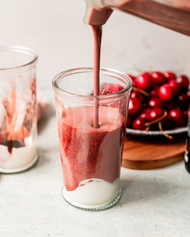 a chocolate cherry protein smoothie being poured into a glass