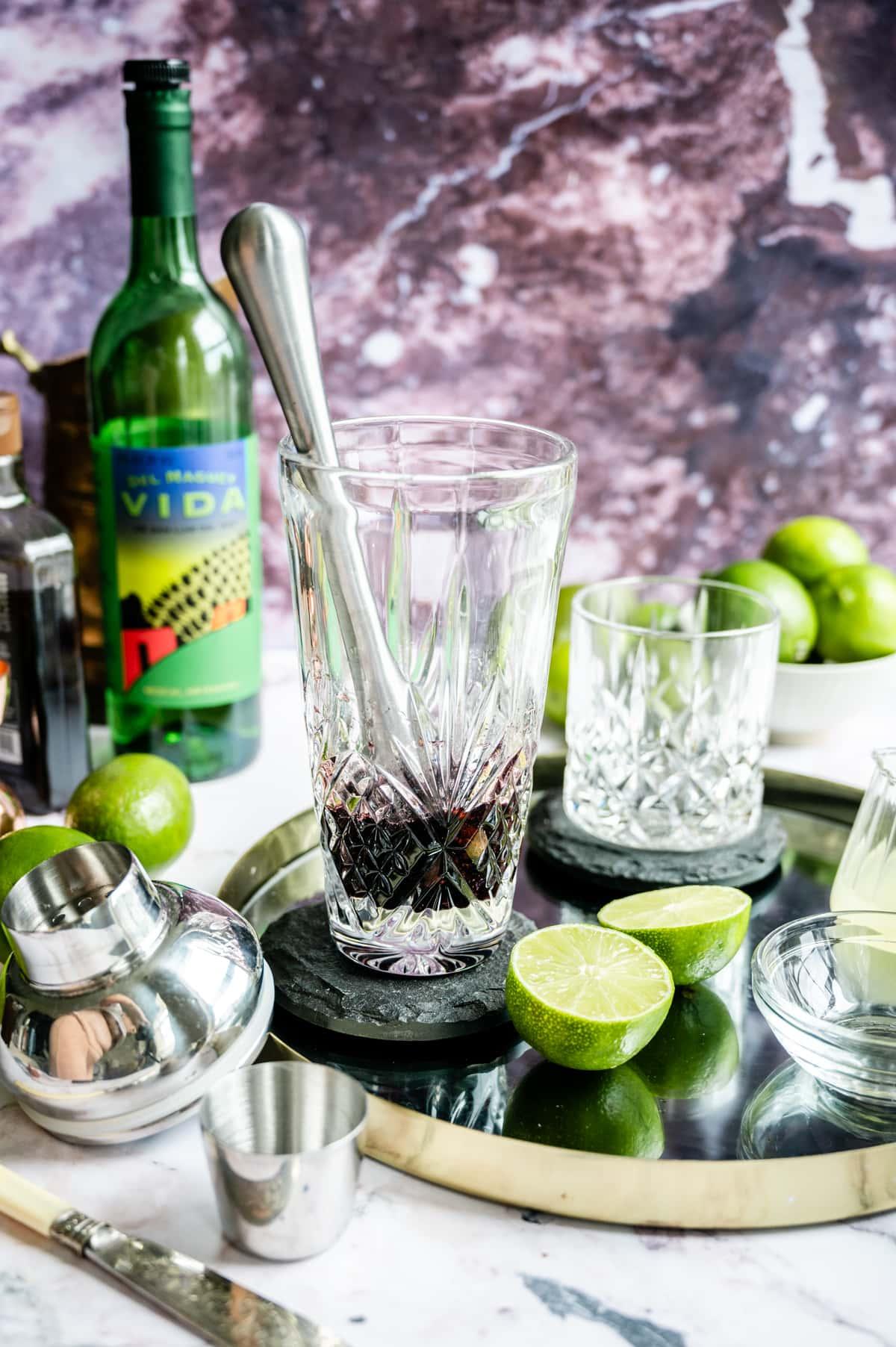 Muddling blackberries and sage in a cocktail shaker