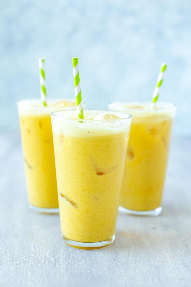 iced golden ginger drink in a glass with ginger slices