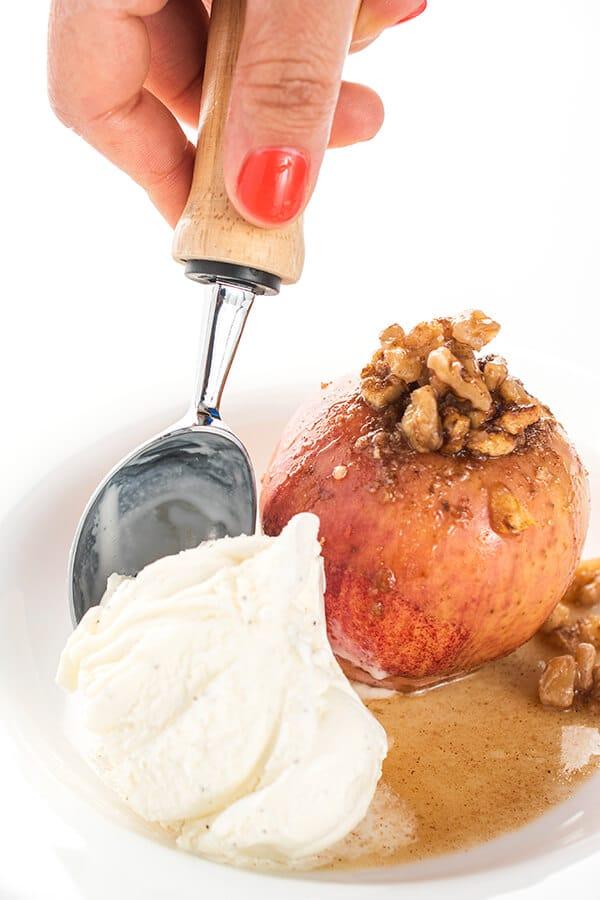 a person serving baked apples with a scoop of ice cream