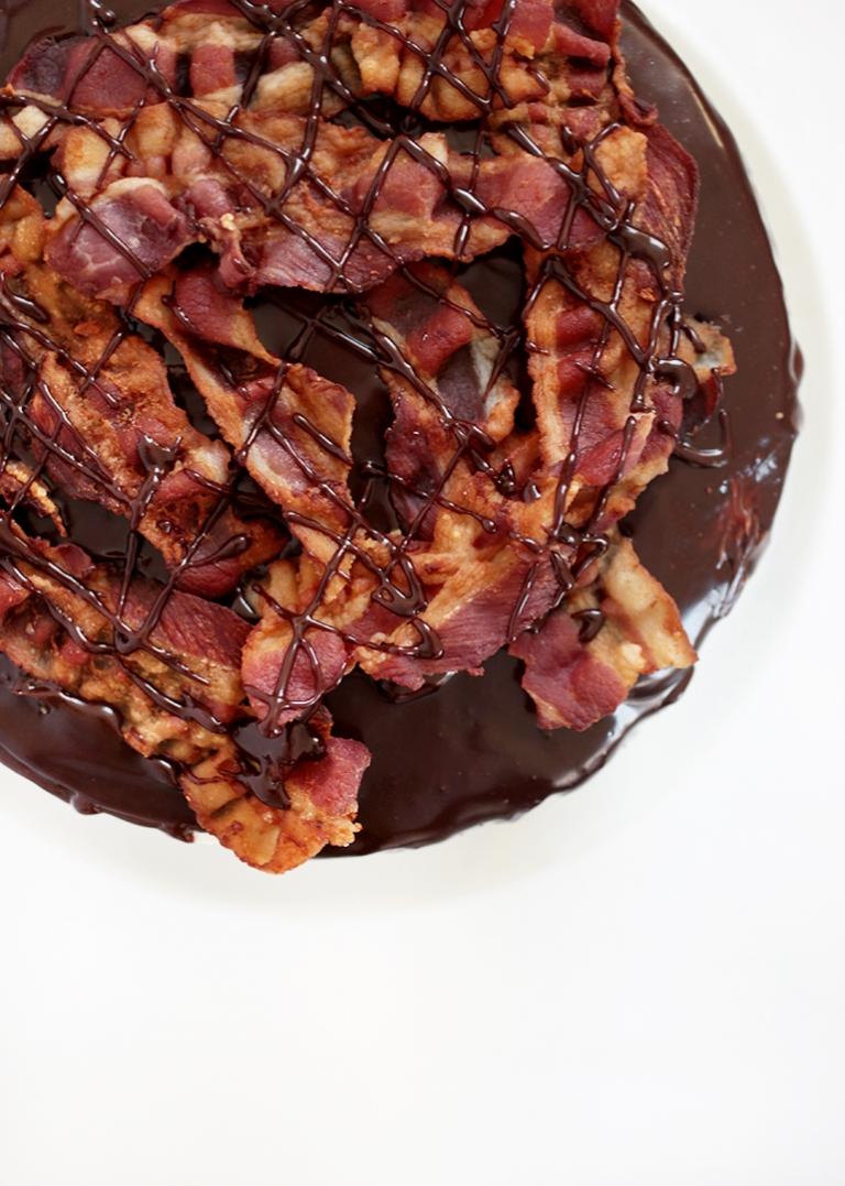 overhead shot of a chocolate maple bacon layer cake with a slice being taken out