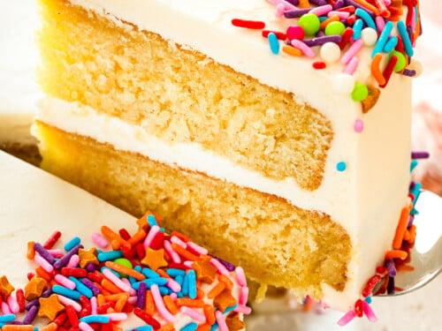 a slice of vanilla birthday cake with shimmering sprinkles being served