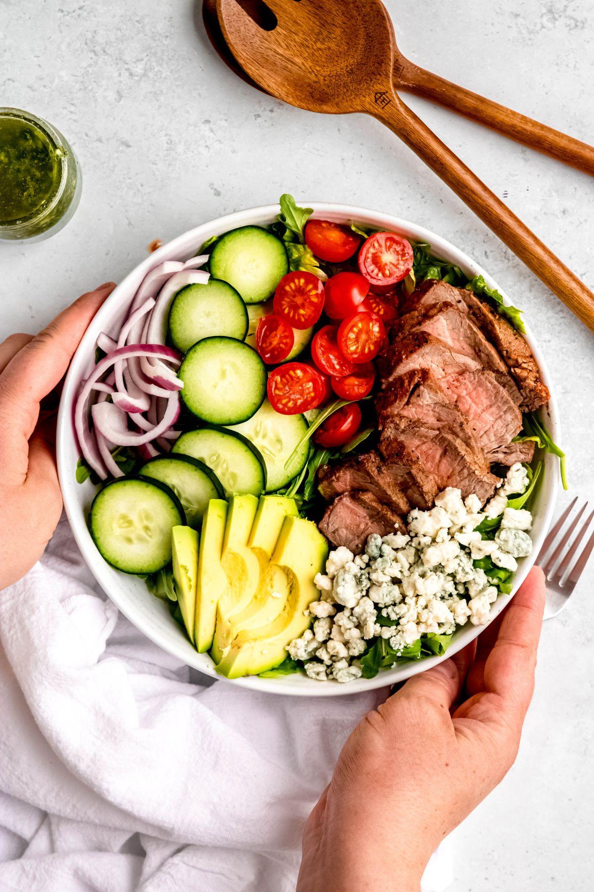 hands assembling a holiday steak salad