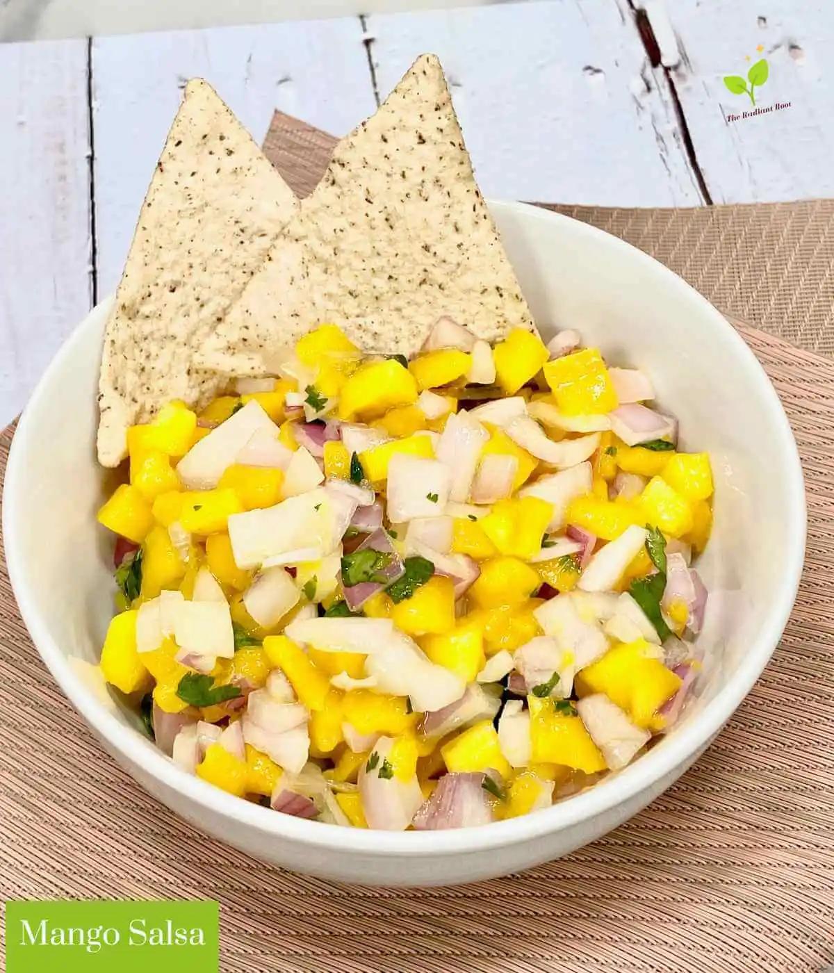 close-up shot of diced mango, red onion, cilantro, and coconut flakes being mixed in a bowl