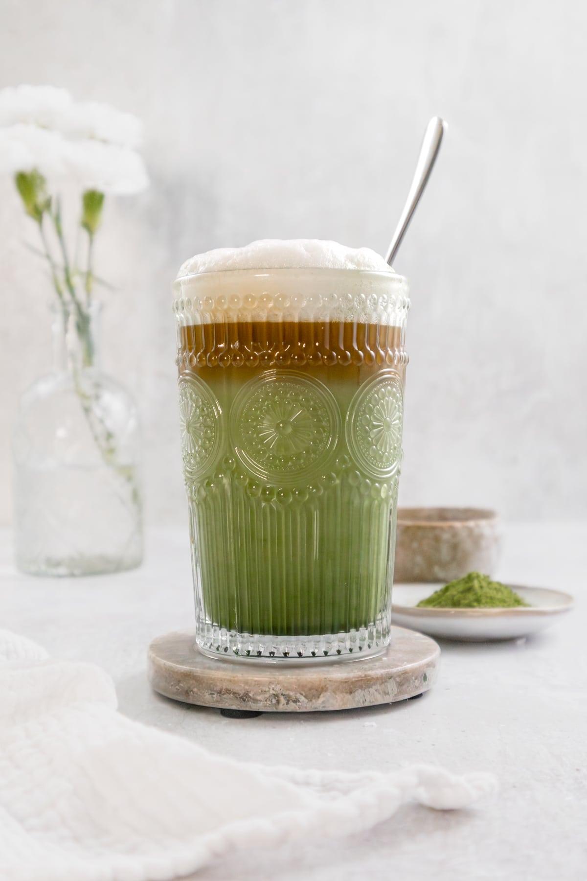 Close-up shot of a Matcha Chai Fusion Latte being poured into a glass, showing the layers
