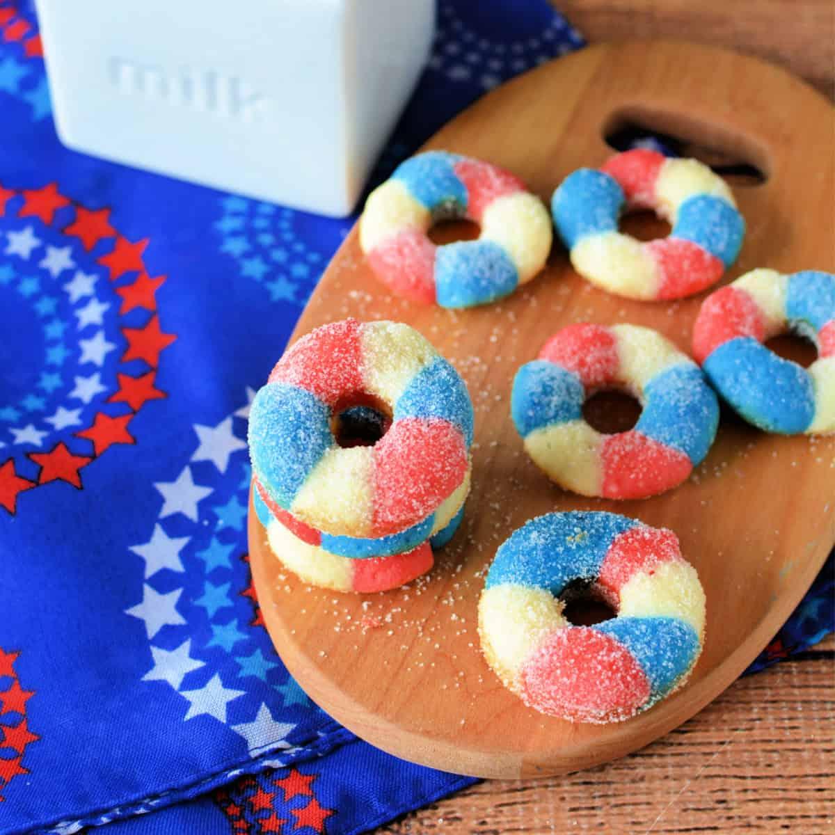 Overhead shot of patriotic mini donuts being decorated with red, white, and blue sprinkles.