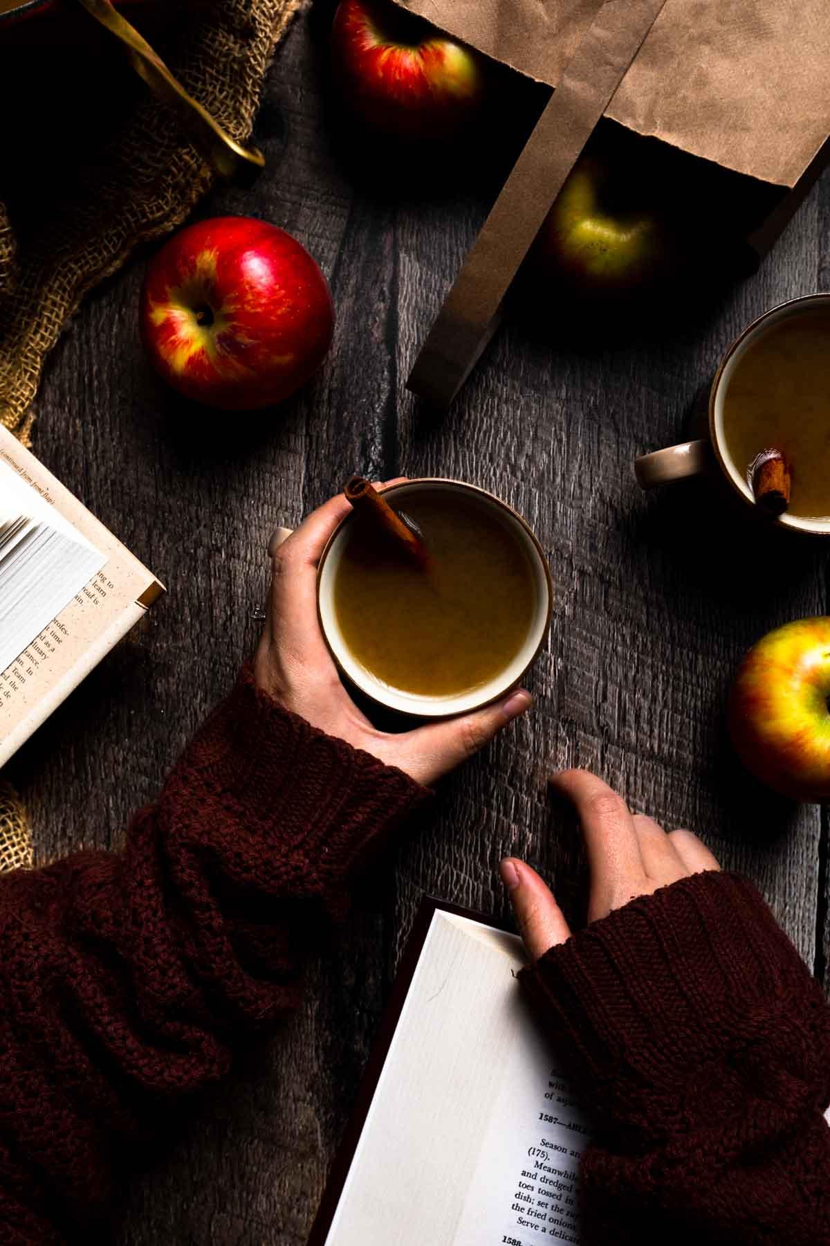 a person holding a mug of spiced apple protein drink in a cozy setting