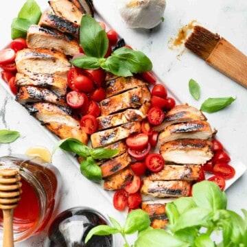 overhead shot of grilled chicken with balsamic tomatoes on a platter