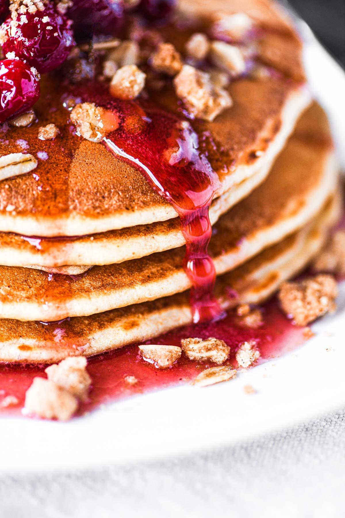 stack of cranberry almond gluten-free pancakes with syrup dripping down