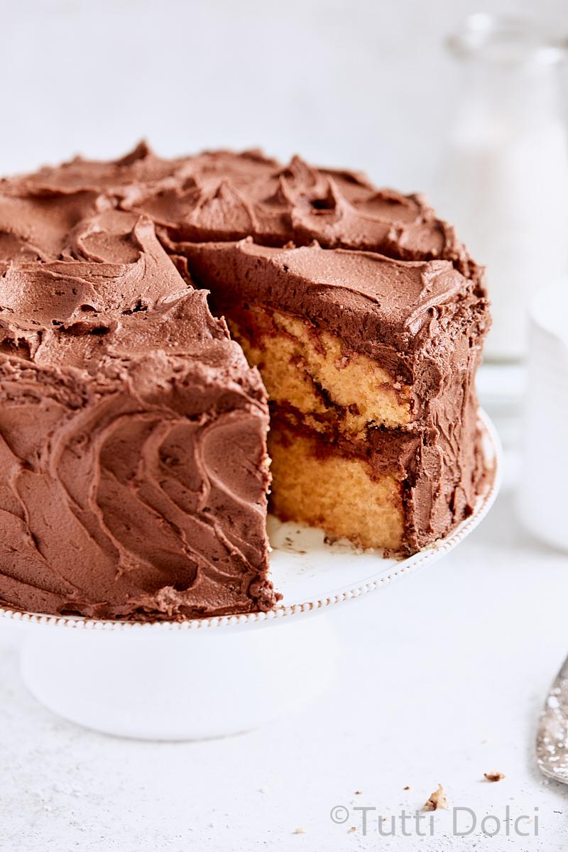 Chocolate Nutella Swirl Layer Cake on a stand with a slice cut out, showcasing the layers