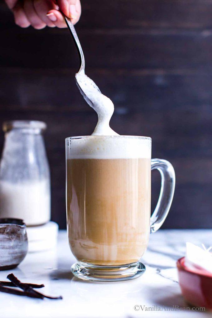Pouring frothed milk into a mug with matcha and Earl Grey tea