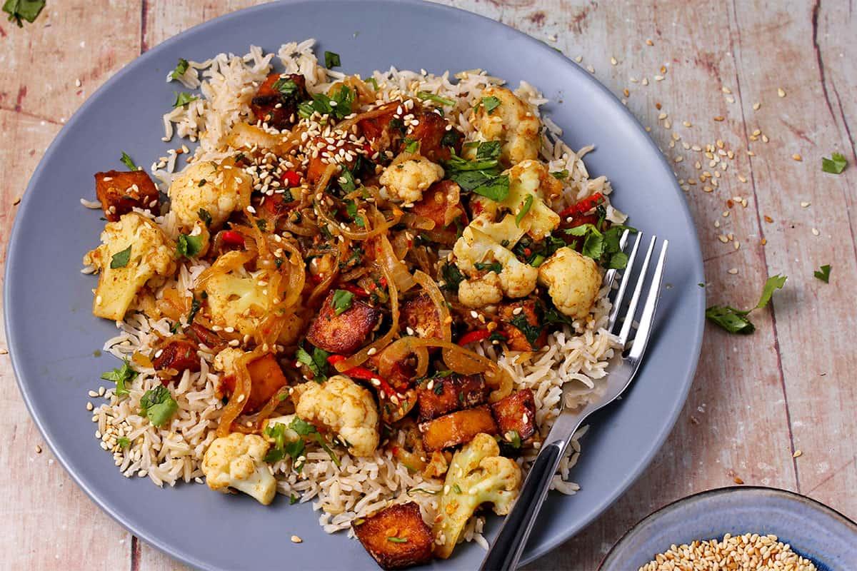 Cauliflower rice stir-fry with tofu being cooked in a wok