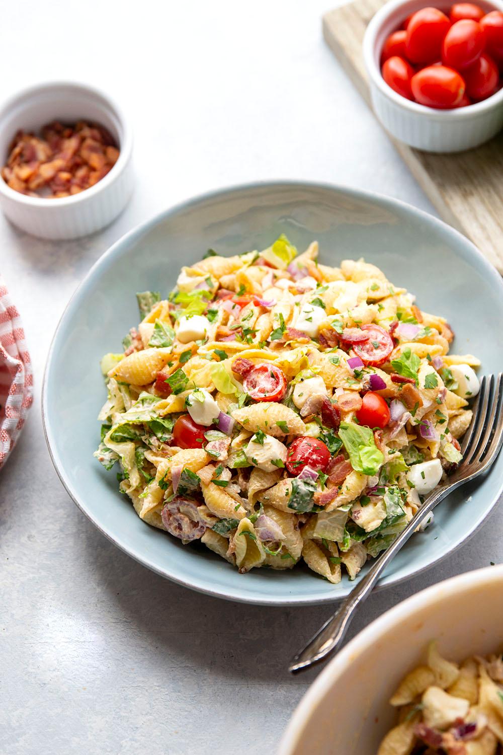 Close-up of a BLT pasta salad with chipotle mayo being tossed in a bowl