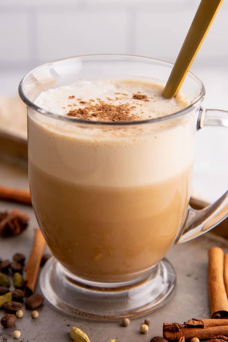 close-up shot of maple cinnamon chai latte being poured into a clear glass mug