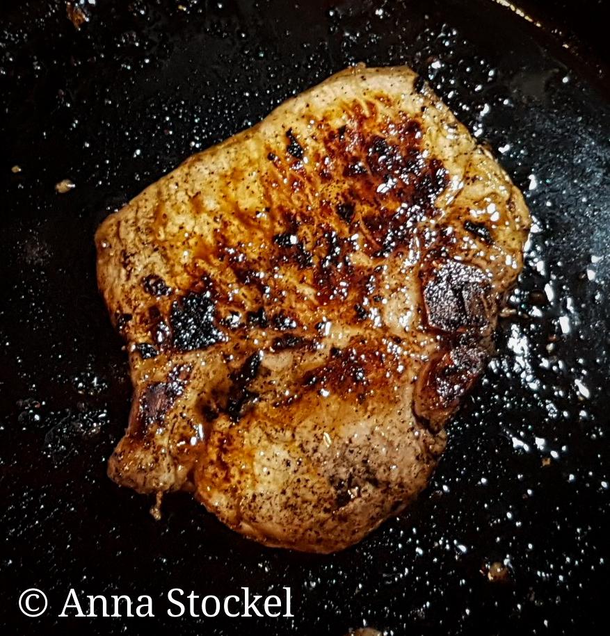 Pork shoulder being seared in a skillet
