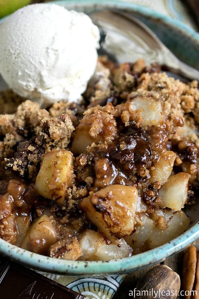Slice of dark chocolate pear crisp being served, with a scoop of vanilla ice cream on the side