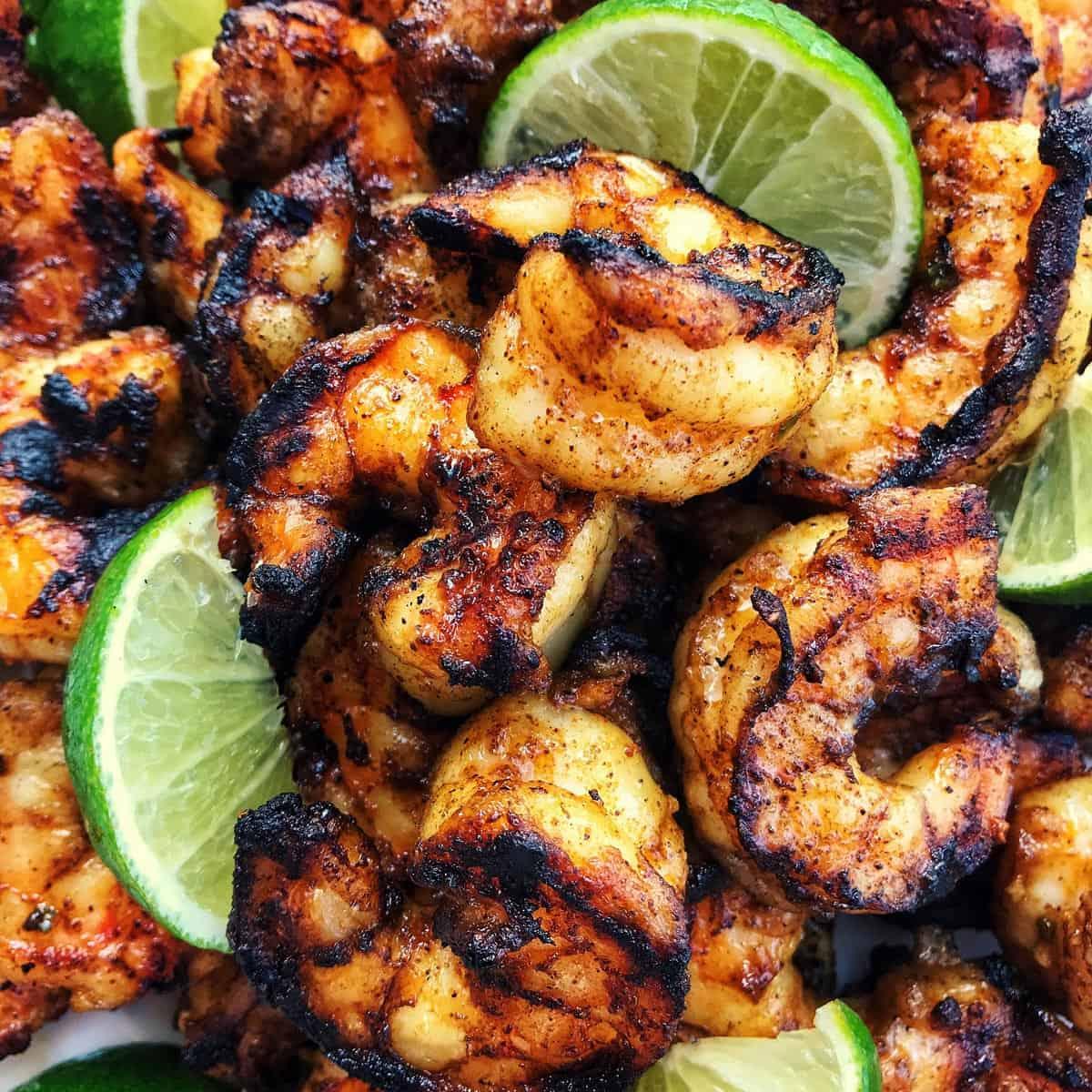 close-up of grilled margarita shrimp skewers with lime wedges