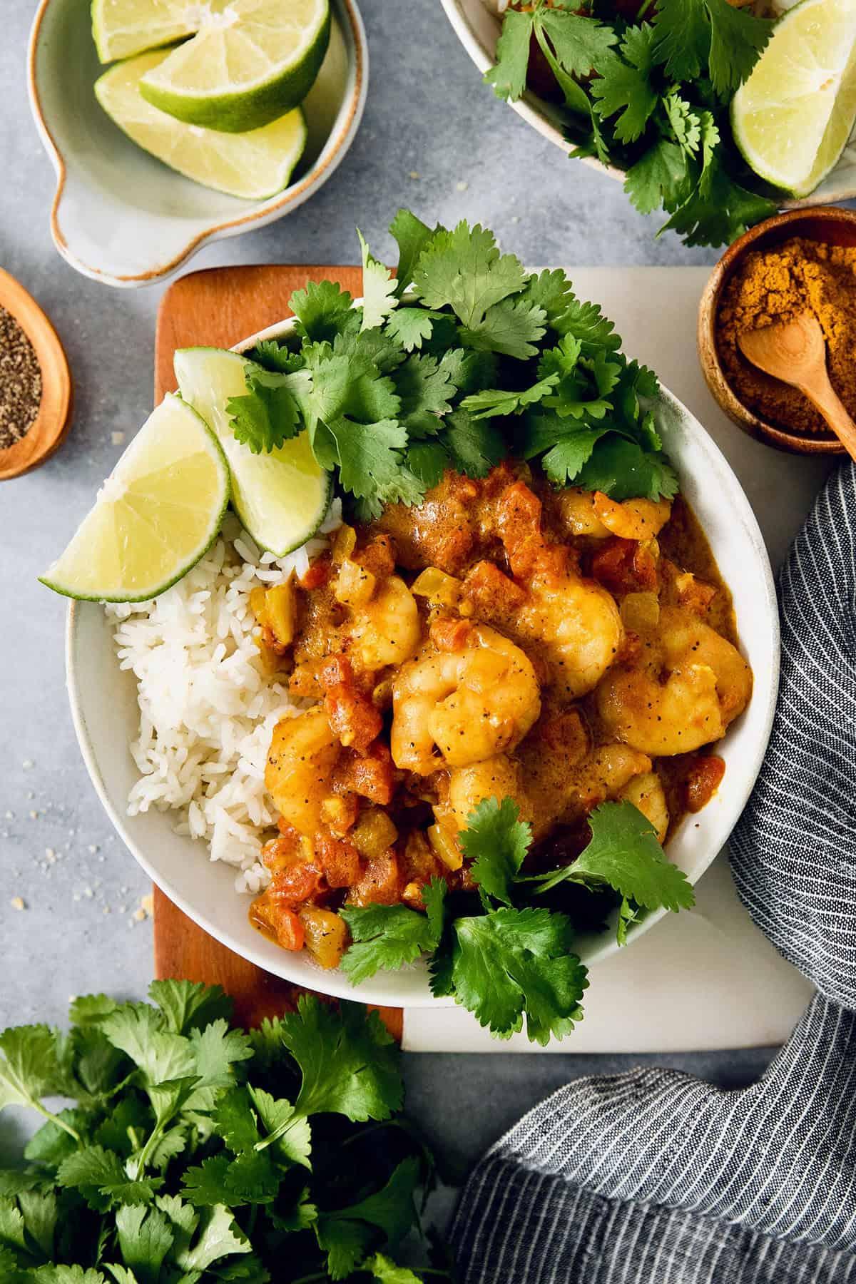 overhead shot of a table setting with bowls of coconut chicken quinoa curry, garnished with cilantro and lime wedges