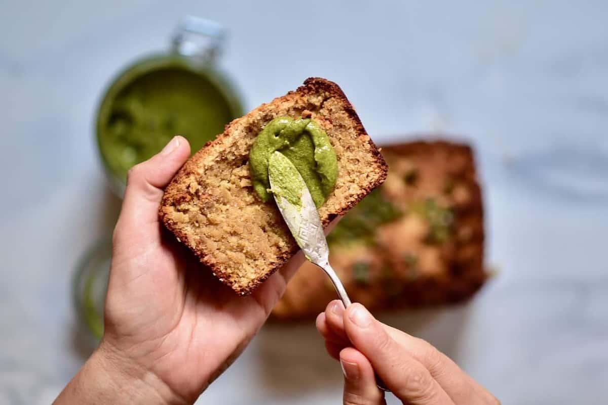 a person holding a slice of gluten-free banana bread with a happy expression