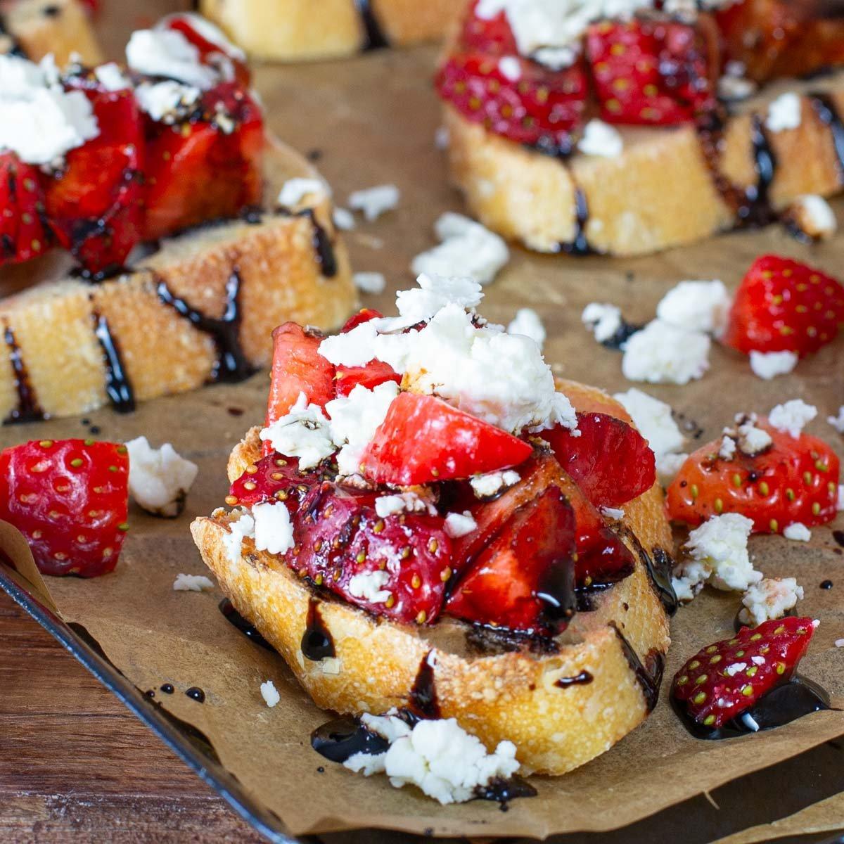 Overhead shot of freshly made brioche toast with strawberries and feta on a wooden board