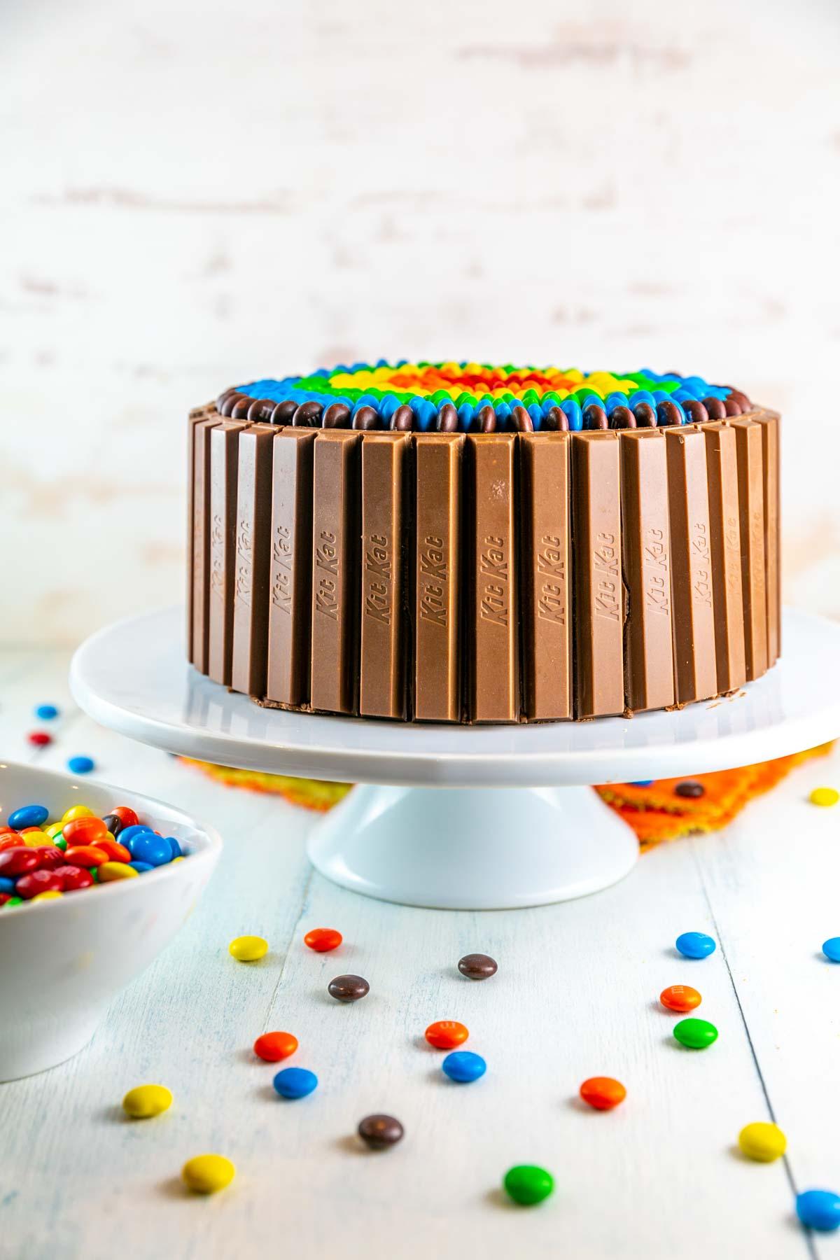 a person decorating a vanilla cake with M&Ms
