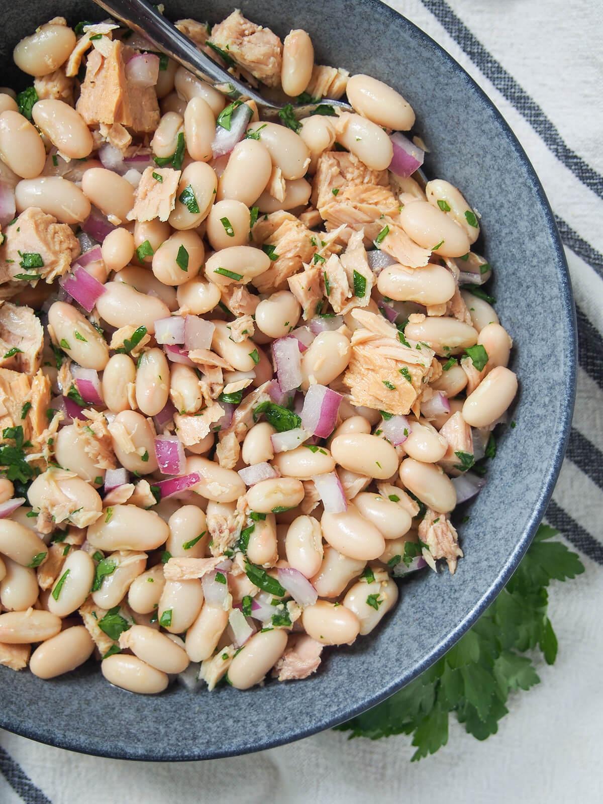 close-up shot of the white bean and tuna salad being mixed in a bowl