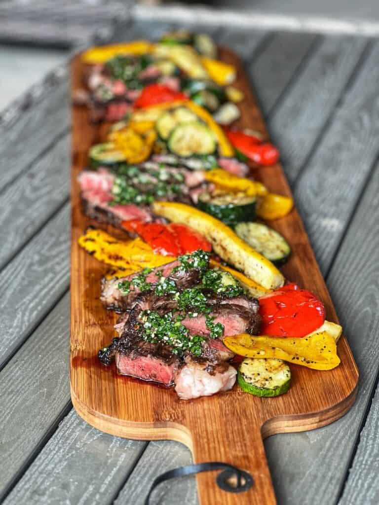 Black garlic and rhubarb relish on a wooden board with grilled steak
