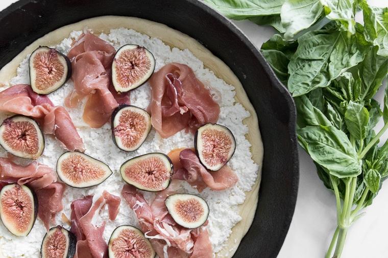 Close-up of a fig and prosciutto pizza being sliced