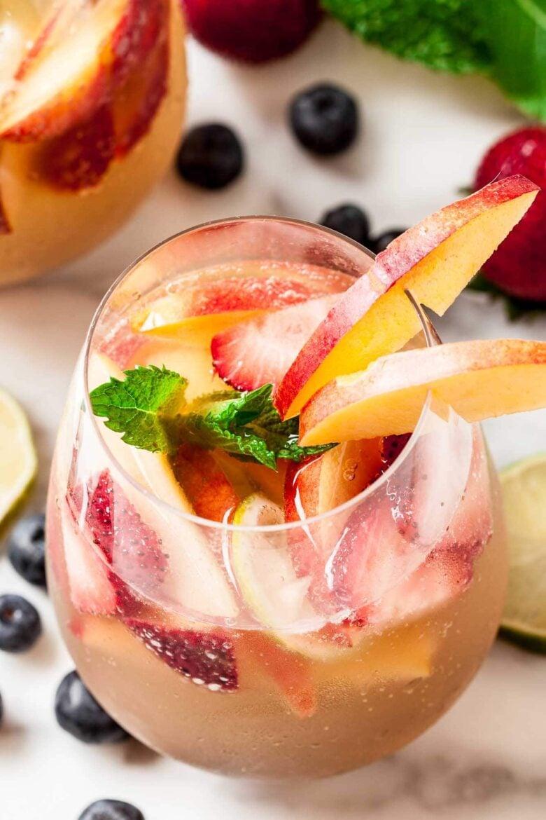 close-up shot of Italian Summer Sangria with peaches and basil in a wine glass
