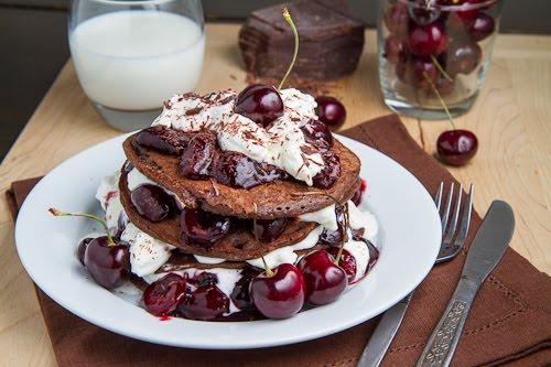 overhead view of a plate of Black Forest gluten-free pancakes with a dollop of whipped cream and fresh cherries