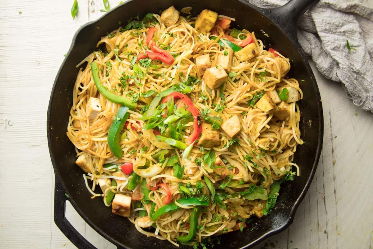 Singapore noodles with tofu and colorful vegetables in a stir-fry pan