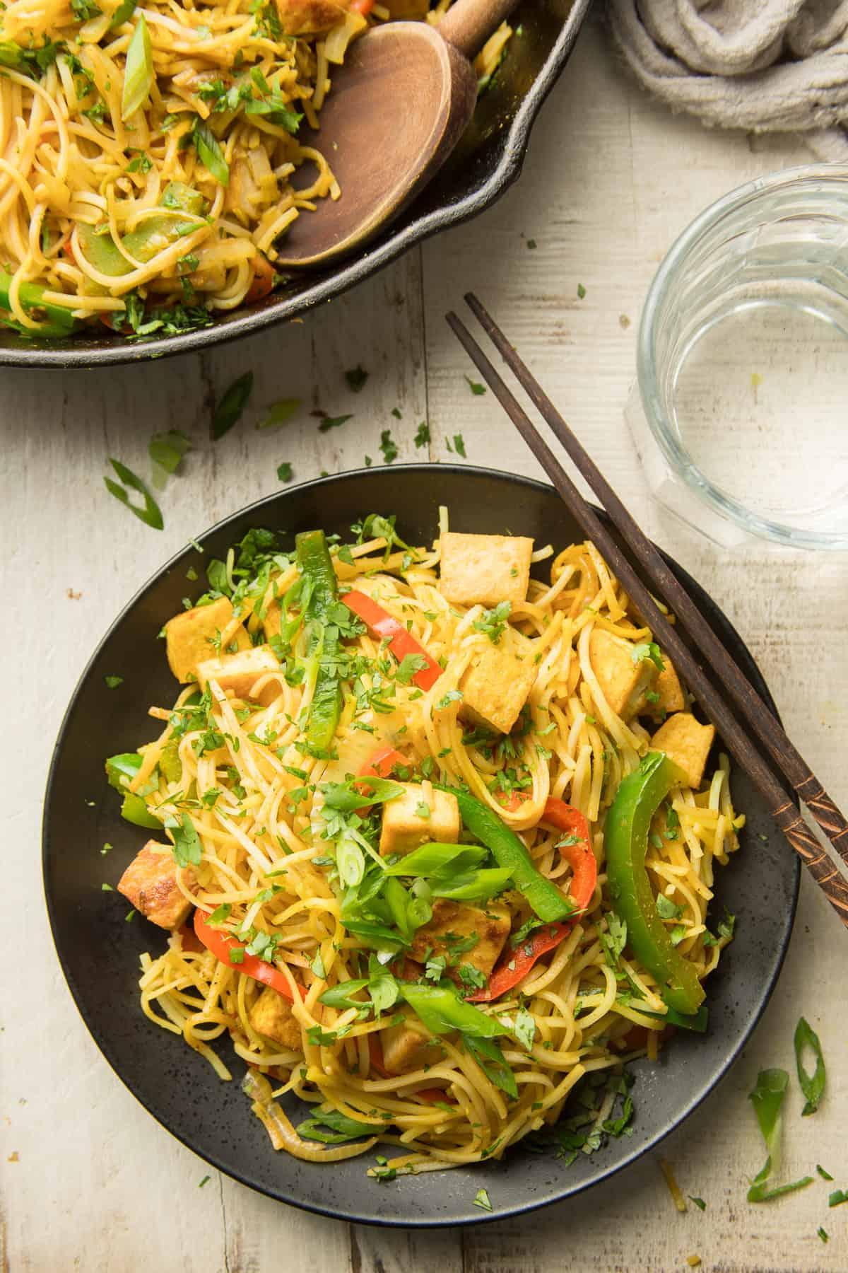 A plate of Singapore noodles tofu stir-fry with chopsticks ready to eat