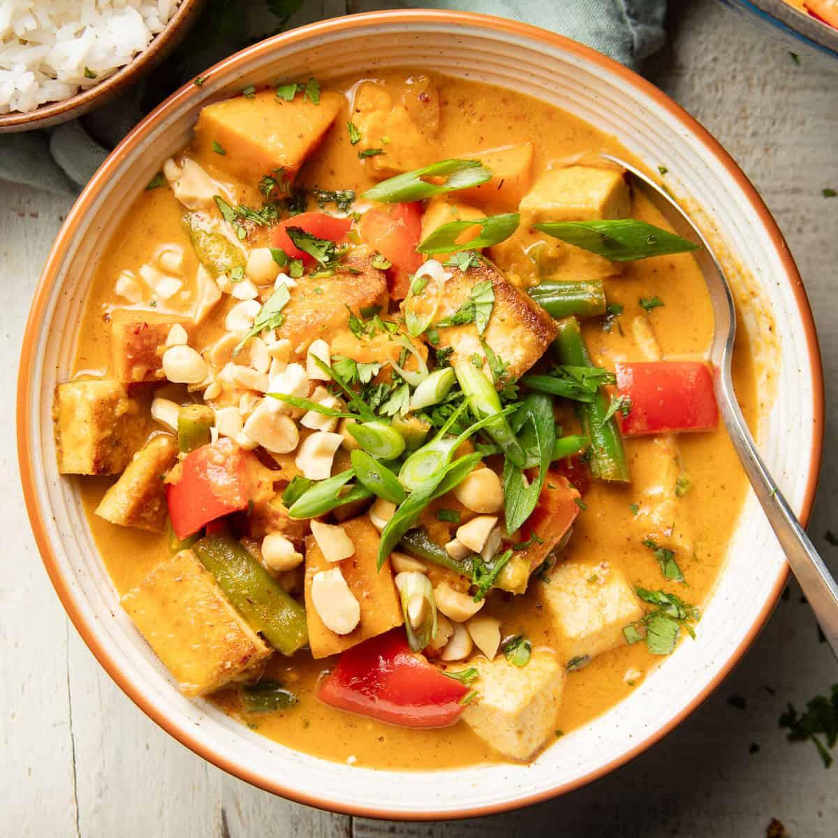 overhead shot of macadamia nuts being added to a pot of simmering massaman curry