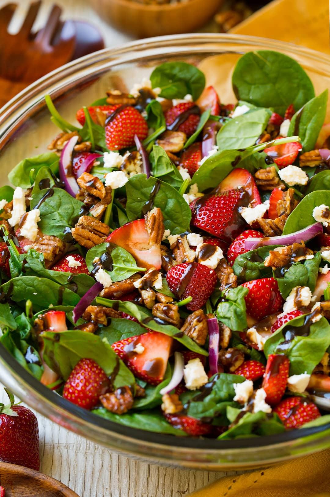 close up shot of strawberry spinach salad being assembled, showing the layering of ingredients