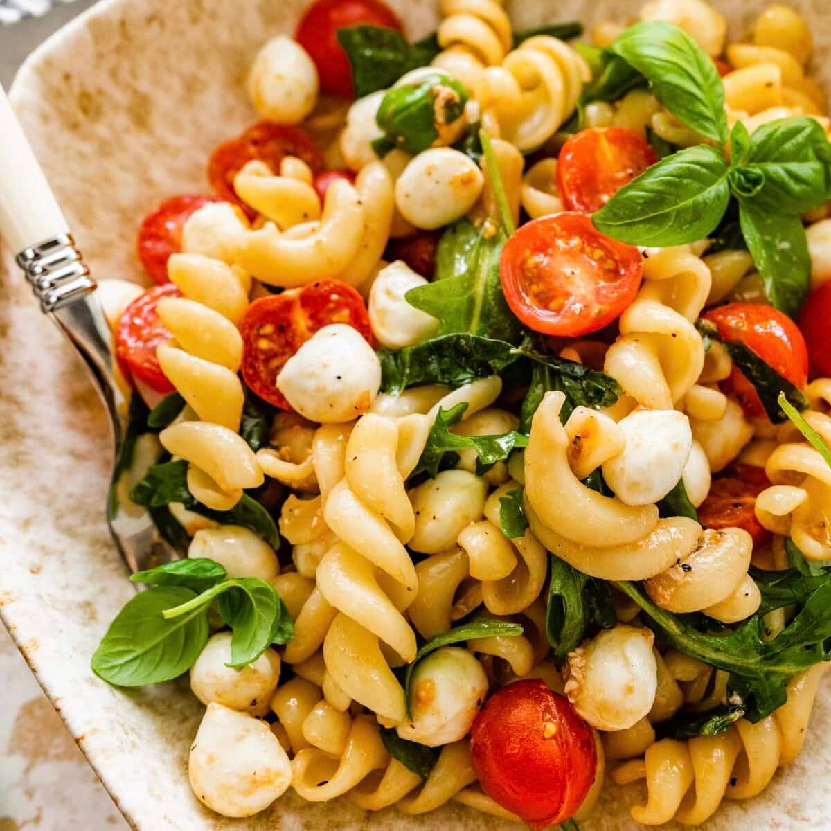 A serving of Caprese pasta salad being enjoyed outdoors in the sunlight
