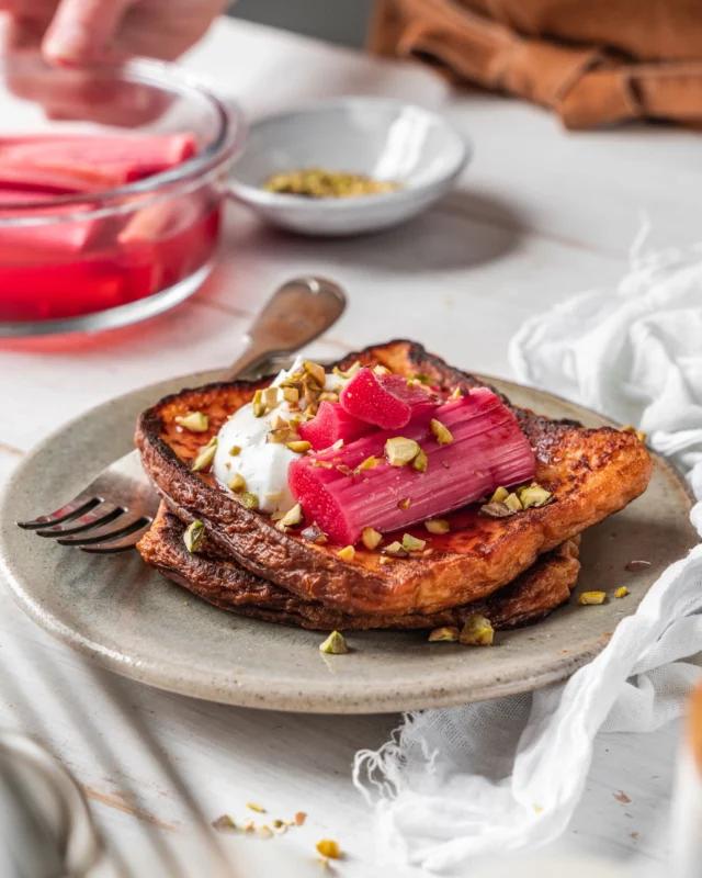 A hand holding a slice of air fryer rhubarb bread, with a blurred background of the air fryer